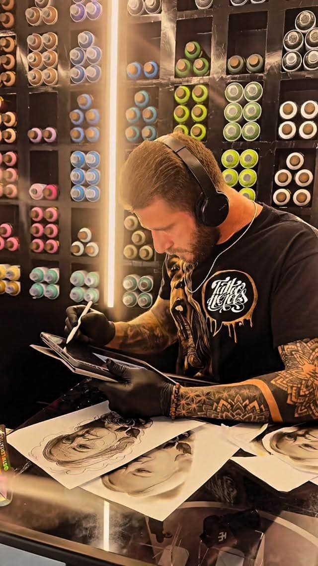 Ramon Vicente tatuando su tablet, studio con vernici spray sullo sfondo